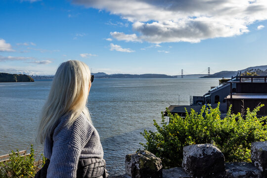 Senior woman viewing Golden Gate Bridge in distance across San Francisco Bay 