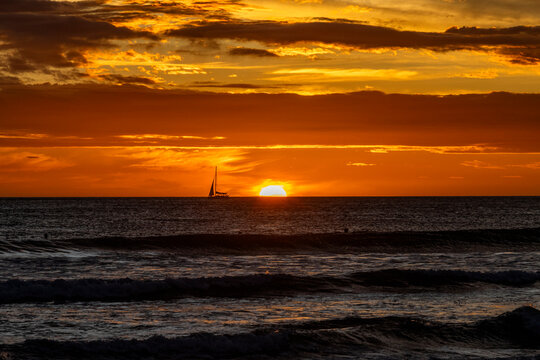 Silhouette of sailboat on sea horizon at sunset