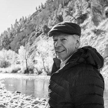 Portrait of smiling senior man by river, black and white