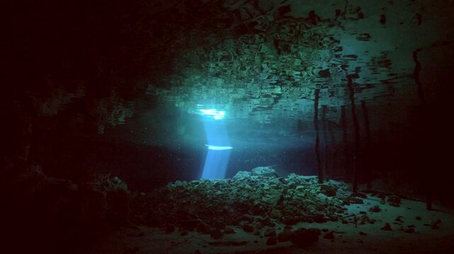 Reflected sunlight creates shimmering patterns on cave floor and walls in Cenote Dos Ojos, Quintana Roo, Mexico