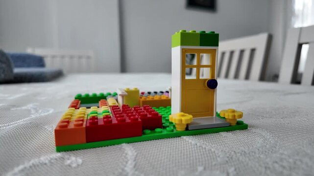 Person finishing a colorful toy building with a green block, educational play and childhood development concept.