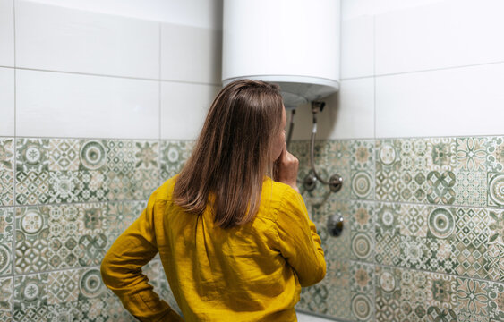 Worried woman looking at broken water heater.