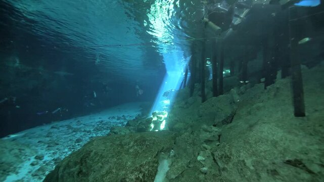 Light rays enter from surface creating bright beams over rocky underwater terrain in Cenote Dos Ojos, Quintana Roo, Mexico