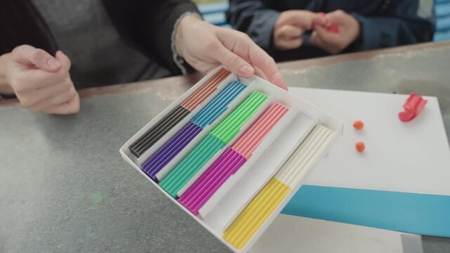 Caucasian teacher arranging colorful math rods on tray, careful hands sorting counting pieces on desk, preparing tactile manipulatives for school lesson, calm instructional atmosphere, neat supplies