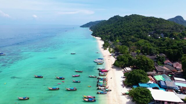 Beautiful drone footage of a beach on Koh Phi Phi in Thailand. Boats are anchored in the turquoise blue water.