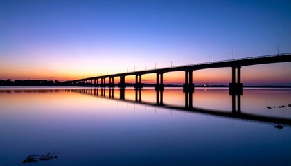 Obraz premium A serene sunset scene with a long bridge spanning across calm waters
