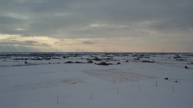 Wide drone shot of wind turbines and sun rays in winter.