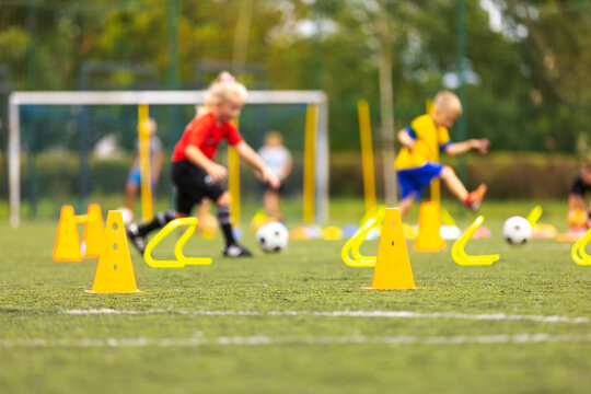 Youth Soccer Speed and Agility Drill. Kids Training with Hurdles and Cones on Outdoor Field. School Sports Class For Kids