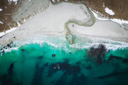Aerial view of the mesmerizing turquoise sea meeting the white sandy beach at Uttakleivveien, creating a stunning contrast against the rugged landscape, Haukland Beach, Nordland, Norway.