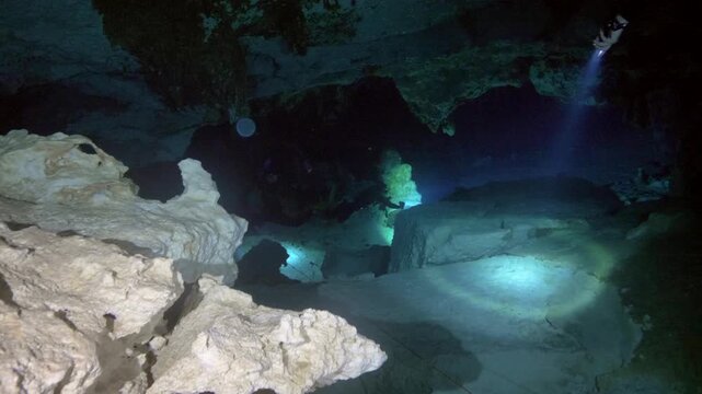 Diver tracks navigation line using light in low visibility cavern in Cenote Dos Ojos, Quintana Roo, Mexico