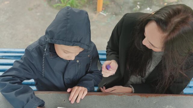 Asian counselor helping child prepare backpack, calm supportive guidance with hands fixing buckle and zipper, blue backpack and jacket on park bench, transition to school day, building confidence