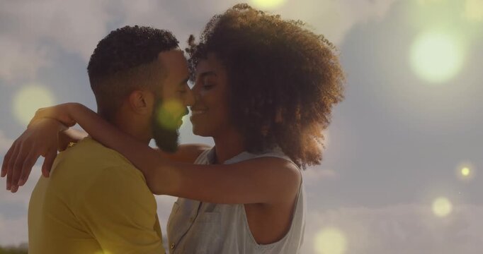 Couple embracing at shore gazing and leaning in tilting back with lens flare for romantic marketing