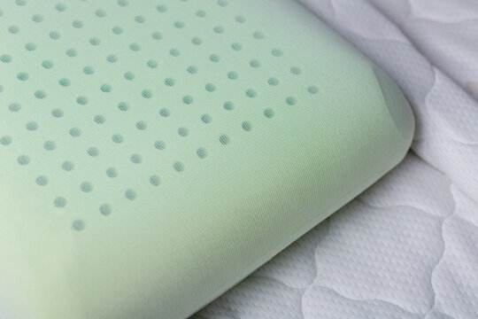 Close-up of a memory foam pillow with perforated surface resting in its natural shape after use. Demonstrates structure, comfort, and ergonomic support of the material.