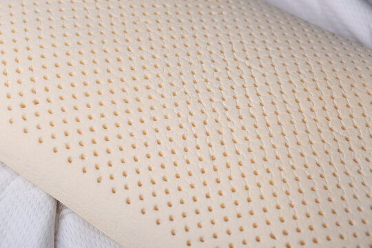 Close-up of a latex pillow without a cover, showing perforated foam structure. Detailed view of breathable material designed for comfort, support, and airflow.