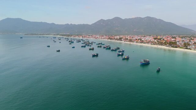 Visitors enjoy Dok Let Beach in Vietnam while colorful fishing boats dot the water. The coastline features soft sand, lively community activities, and mountain backgrounds