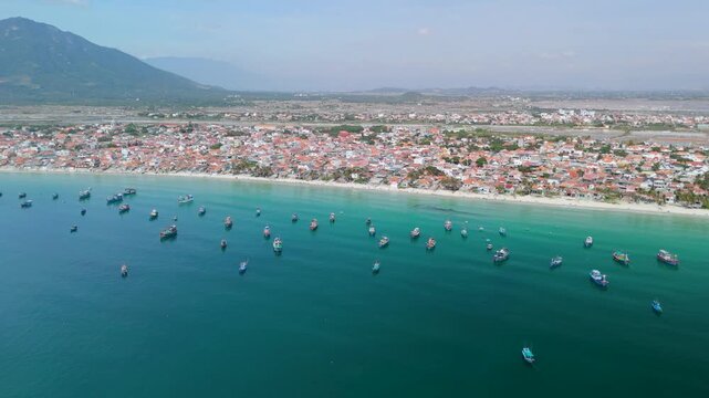 Dok Let Beach in Vietnam shows many boats in the water near the shore. People can be seen enjoying the beach and the bright sun under a clear sky. It is a lively place to visit