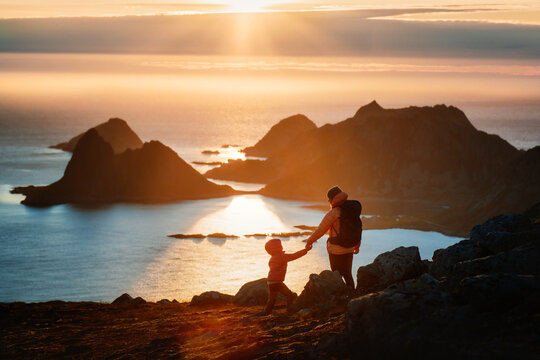 Family travel in Norway parent and kid on summer vacations hiking trip together, mother with child enjoying midnight sun sea and Vesteralen islands view, people explore trails outdoor in mountains