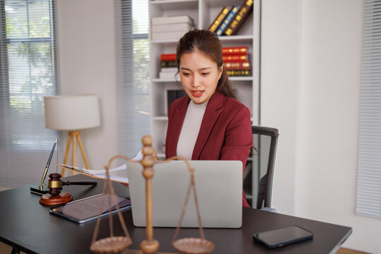 Asian female lawyer working at desk with laptop and legal items