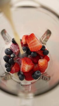 Milk Cream Pouring Into Fresh Strawberry and Blueberry Glass &ndash; Healthy Fruit Dessert Drink