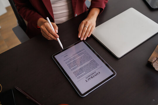 Businesswoman digitally signing contract on tablet with stylus