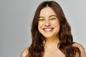 Naklejka premium Bold beauty shines with vibrant green eyeshadow and a joyful expression in studio