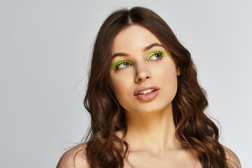 Fototapeta premium Bold makeup showcase featuring a young woman with vibrant green eyeshadow in a studio
