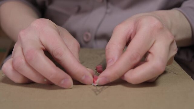 Close-up of a girl creating art using a cardboard stencil, tiles and glue