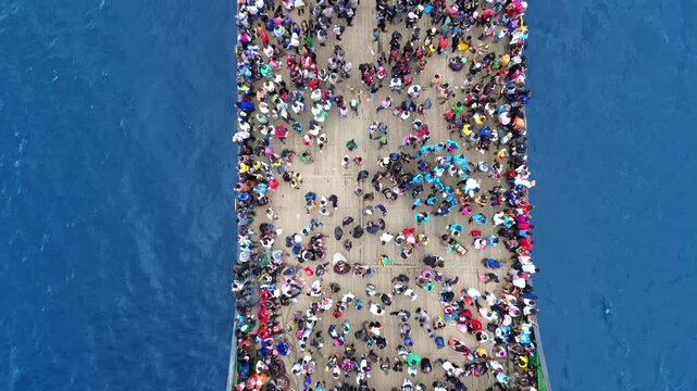 Aerial Top View of Crowded Ferry Deck with Passengers Crossing Blue Ocean
