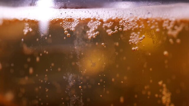 Close-up of cold draft beer being poured into glass with frothy foam head