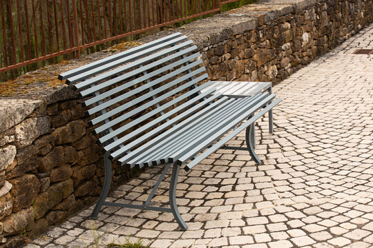 Banco met&aacute;lico en calle empedrada.