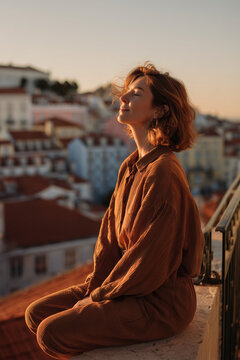 Person practicing mindful meditation and breathwork on a balcony overlooking Lisbon rooftops at sunset