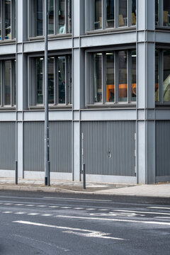 Empty pavement along a modern urban street where building facade and windows form ordered architecture lines and subtle wayfinding navigation cues