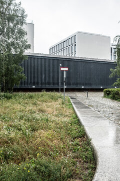 Modern building edge with grass and empty concrete pathway track using strong perspective for urban wayfinding and quiet open space navigation
