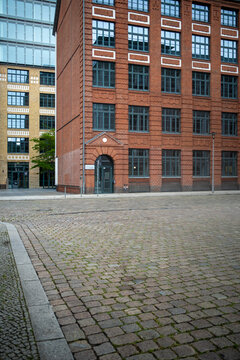 Modern urban courtyard framed by brick building with empty pavement perspective and calm street atmosphere supporting minimal wayfinding orientation