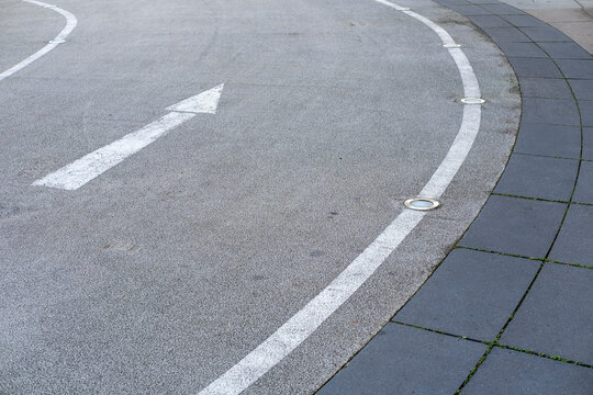 Urban pavement with empty street arrow marking on asphalt road curve showing wayfinding direction and navigation cues in minimal modern streetscape