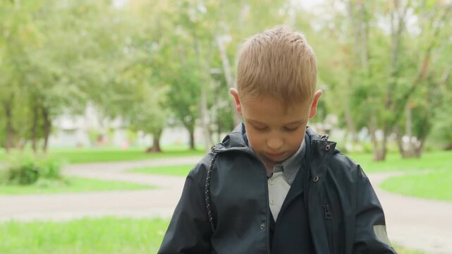 Caucasian boy buttons jacket preparing for school, steady morning routine, neat uniform under hooded coat, small student focuses on collar and zipper, calm determination before heading back to school