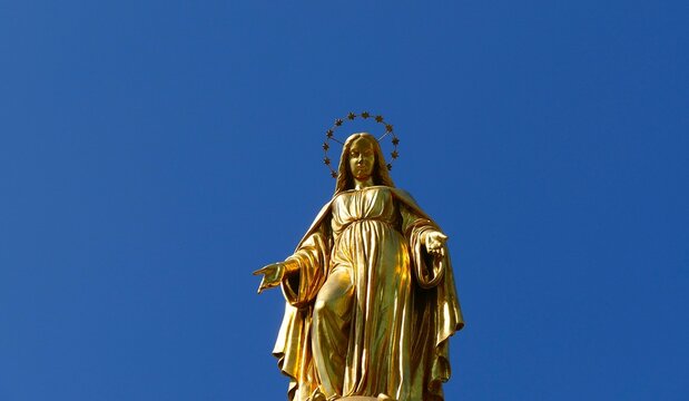 Golden statue of Blessed Virgin Mary high in the blue sky near Zagreb cathedral, religion and faith background
