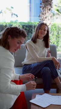 Professional businesswomen discussing contract in modern office, one client signs document while advisor explains terms and conditions of agreement.