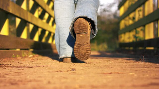 Foot in boots walking across narrow wooden bridge