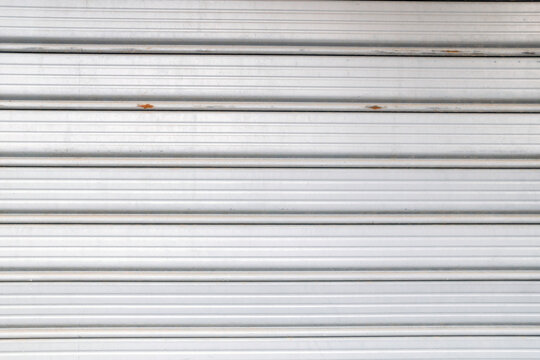 Detailed view of grey metallic security rolling shutters with parallel lines.