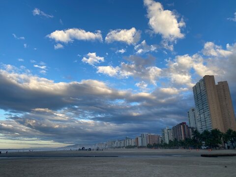 nuvens  e ceu azul em um amanhecer na praia com alguns pr&eacute;dios na orla , bairro canto do forte em  Praia Grande