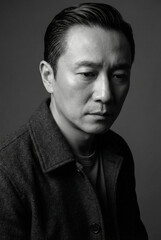 Obraz premium Dramatic monochrome portrait of a serious mature Asian man in a pensive and thoughtful pose.