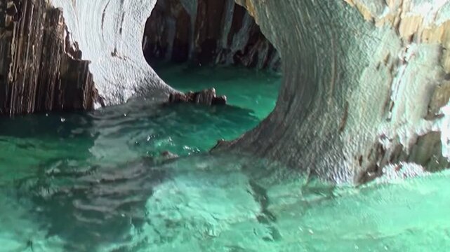 Emerald waters gracefully dance against the smooth, carved rock of Patagonia's Marble Caves. A serene journey through nature's magnificent artistry, showcasing the unique geological beauty.