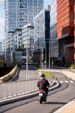 Solo rider on scooter enters a broad curve on modern urban street creating dynamic cityscape lines in paris france under bright daylight