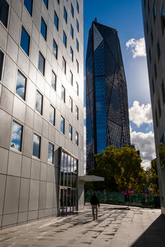 Single pedestrian in modern urban street between tall buildings and glass architecture forming a cityscape scene in paris france under daylight