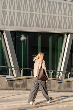 daylight commuter businesswoman walking as urban pedestrian beside modern architecture in stockholm sweden street scene with motion blur lifestyle

