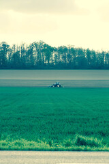 Fototapeta premium Blue-Toned Tractor Plowing a Field