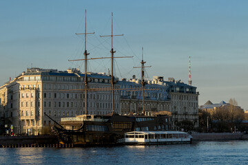 Naklejka premium Frigate ship restaurant moored at the Neva River embankment against the backdrop of historical buildings and the Saint Petersburg TV Tower