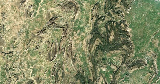 Aerial view on rocky formations among green areas. Camera is moving left and down. Animation based on image by NASA