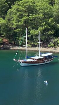 An idyllic wooden gulet peacefully floats on Oludeniz's shimmering azure waters, nestled near Fethiye.
